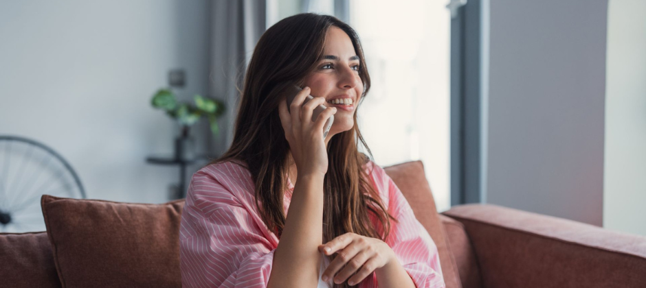 Kvinna i rosa tröja pratar i telefon och ler